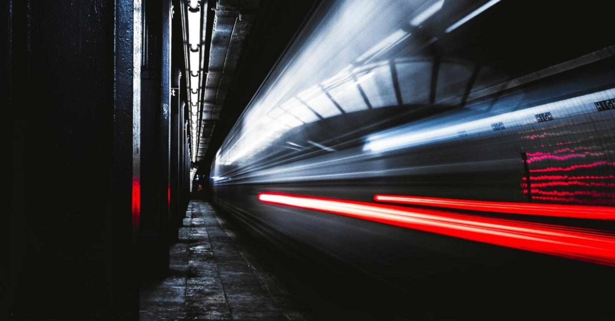 A train at high speed passes through a dark underground tunnel