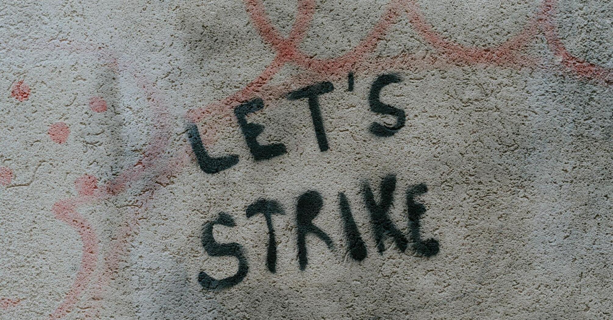 Graffiti with the words 'Let's Strike' on a concrete wall