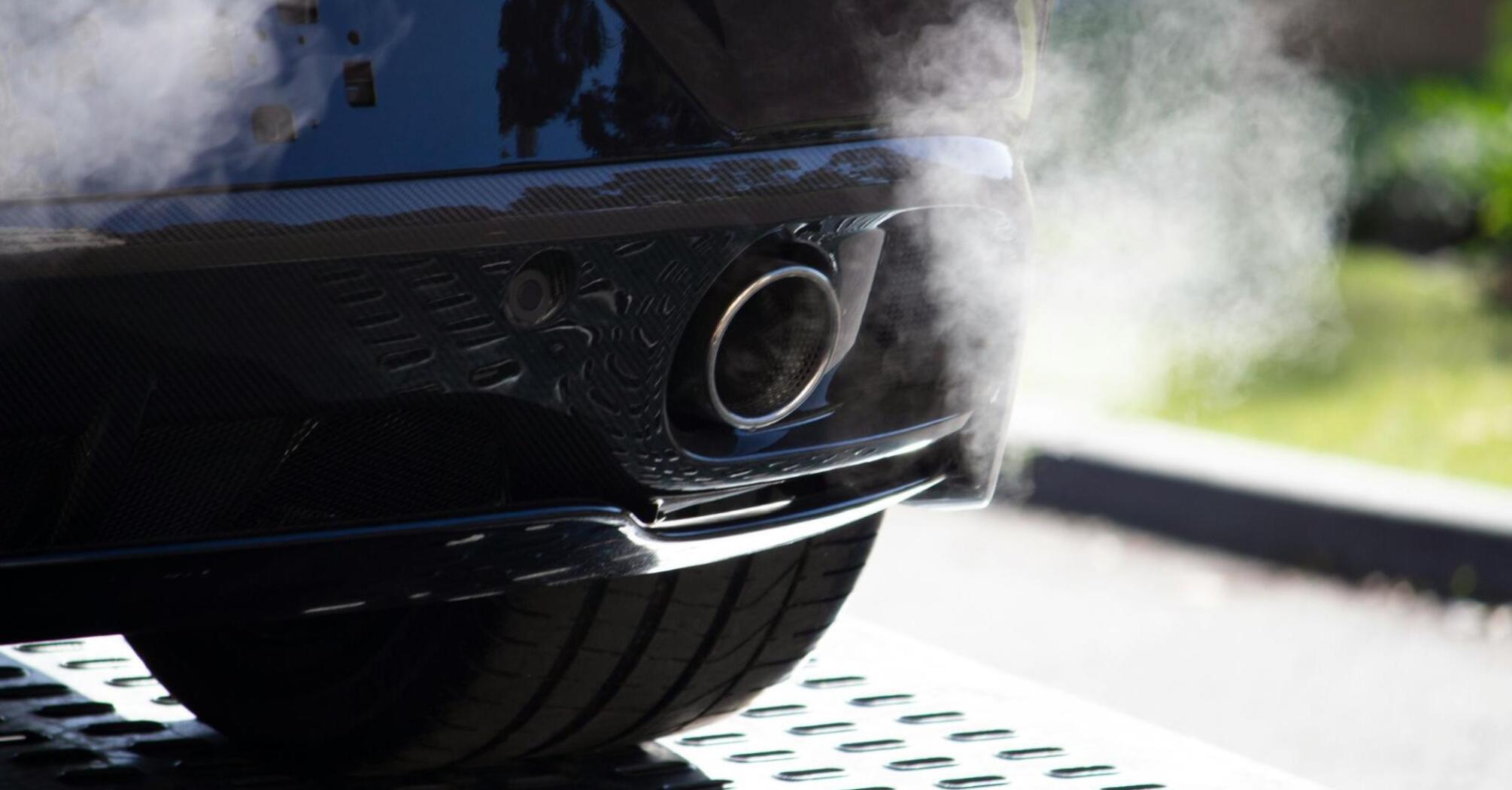 A car smoking from an exhaust pipe on the street on a sunny day