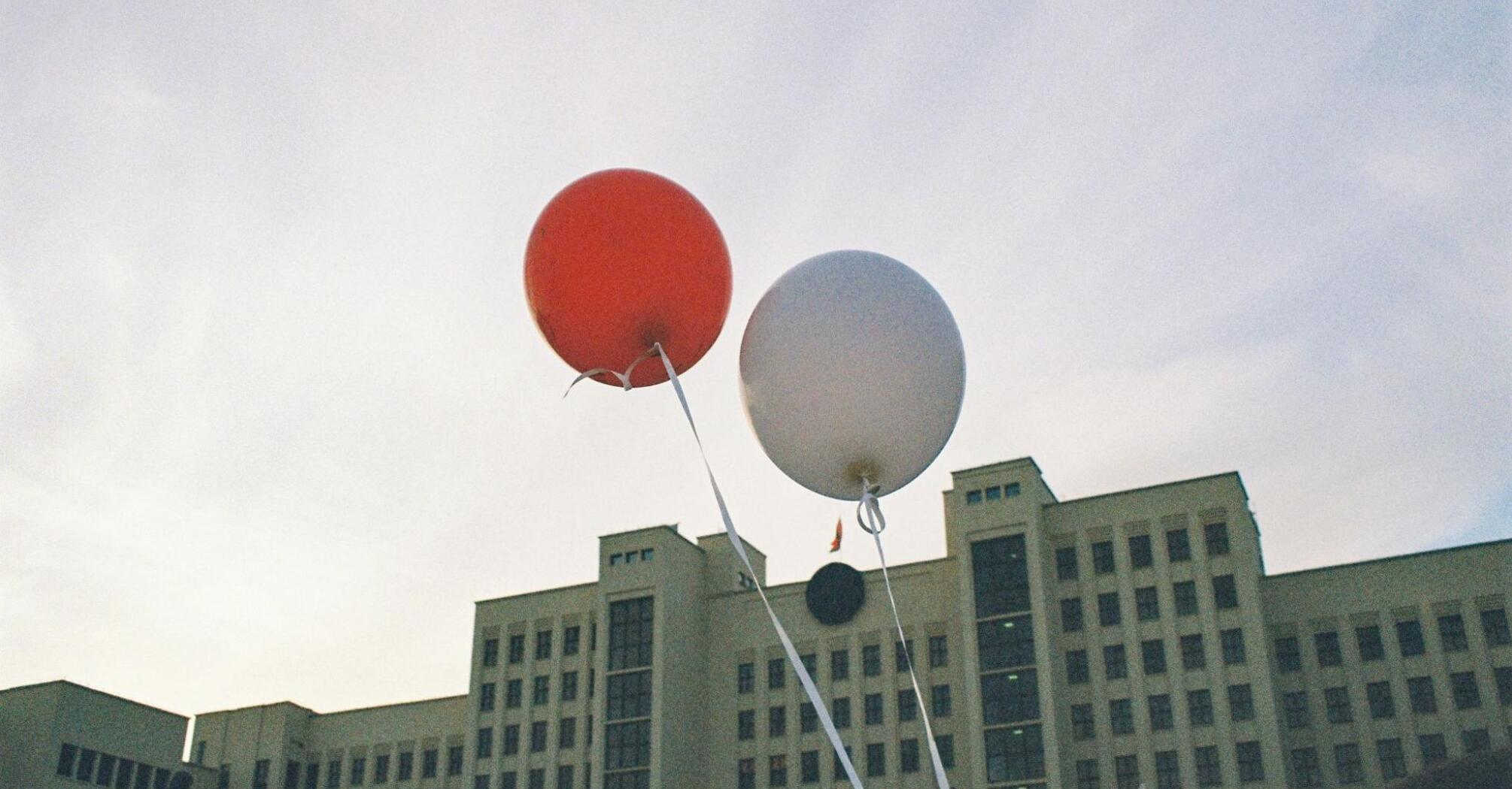 Baloons flying in the sky in front of old building