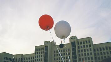 Baloons flying in the sky in front of old building