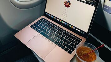 Laptop and drink on an airplane tray table