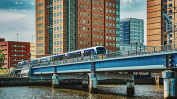 A train crossing a bridge in an urban area with tall buildings in the background