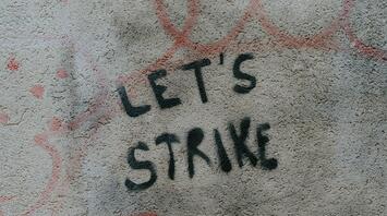 Graffiti on a wall with the words 'LET'S STRIKE' spray-painted in black