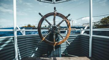 The helm on the deck of a ship overlooking the ocean