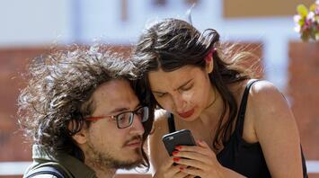 A young couple looks tensely at the smartphone screen