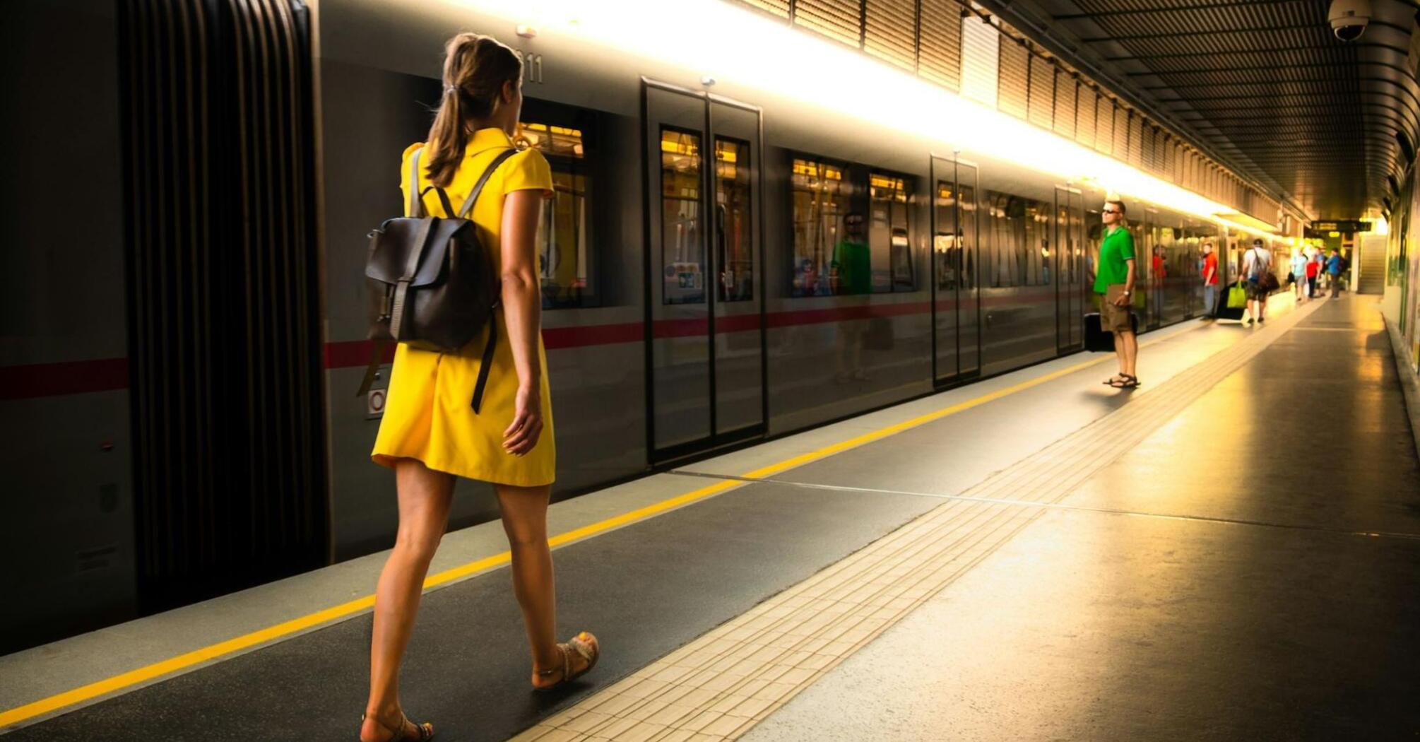 Woman in a yellow dress walking along a train platform