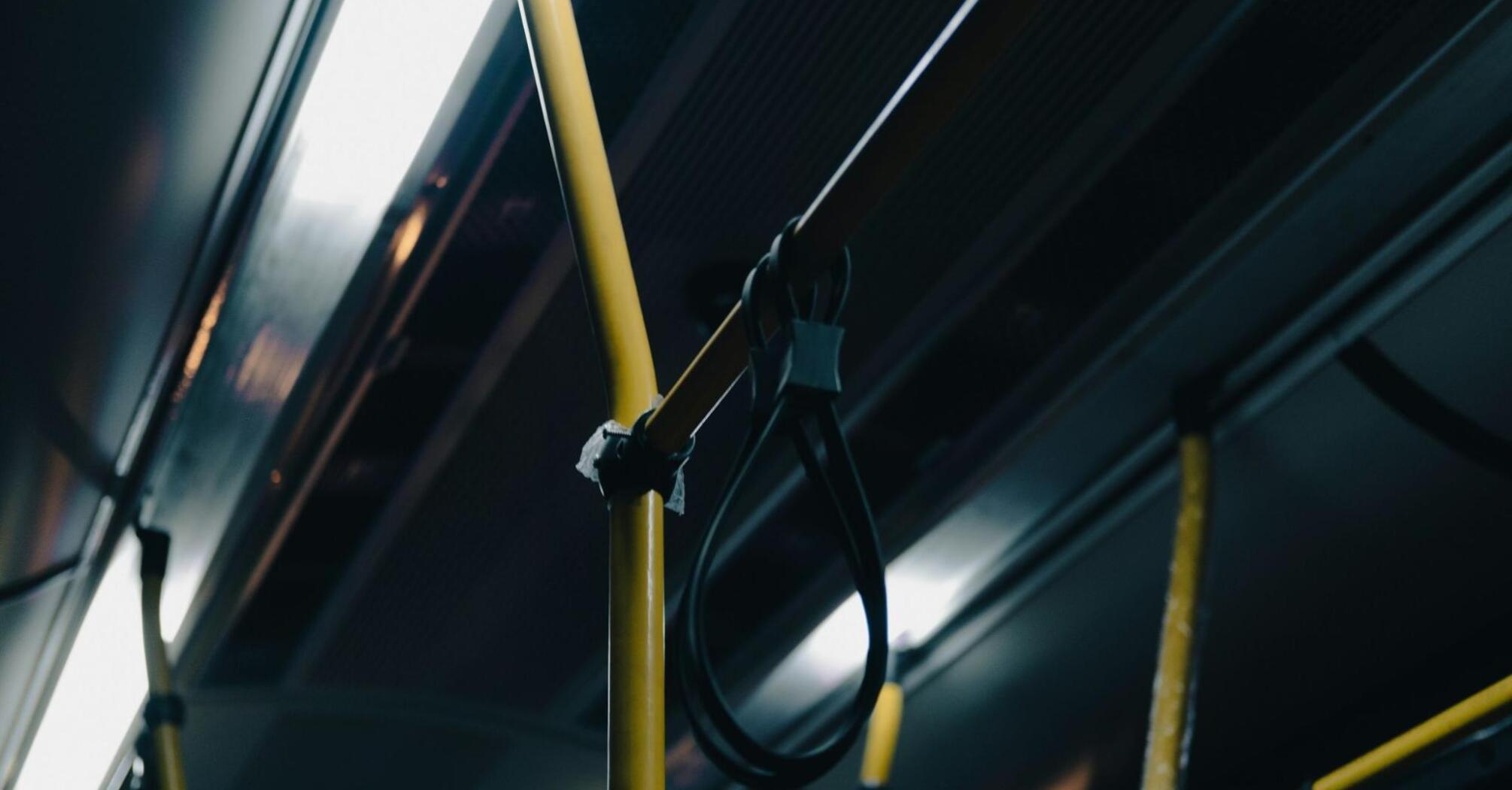 Interior of a bus with yellow poles and hanging straps