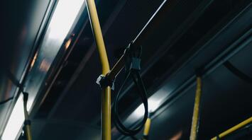 Interior of a bus with yellow poles and hanging straps