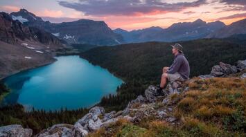 A climber admires the picturesque lake and mountain peaks at sunset