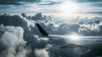 Airplane wing flying above the clouds at sunset