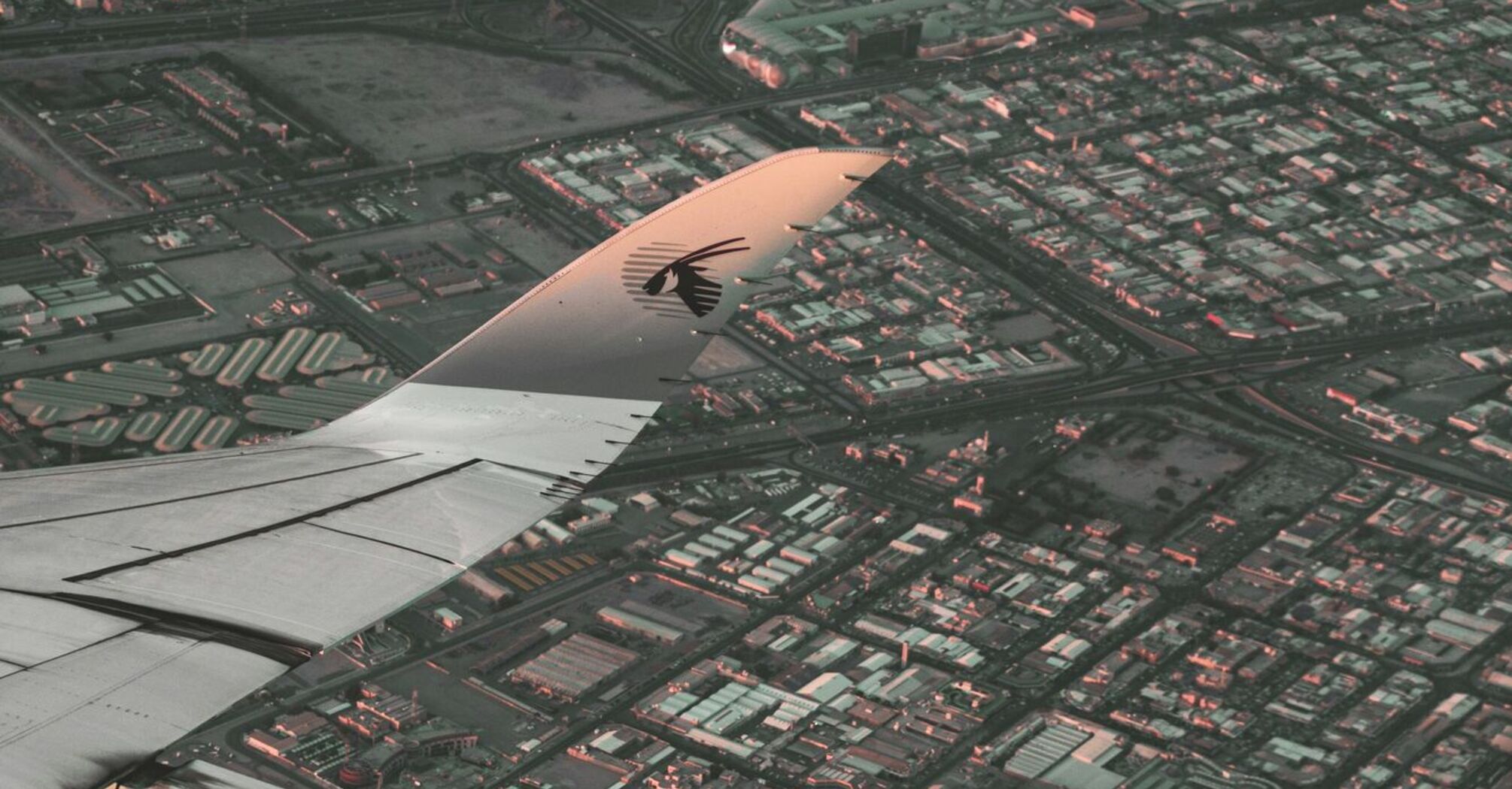 Aerial view from a Qatar Airways plane over a cityscape