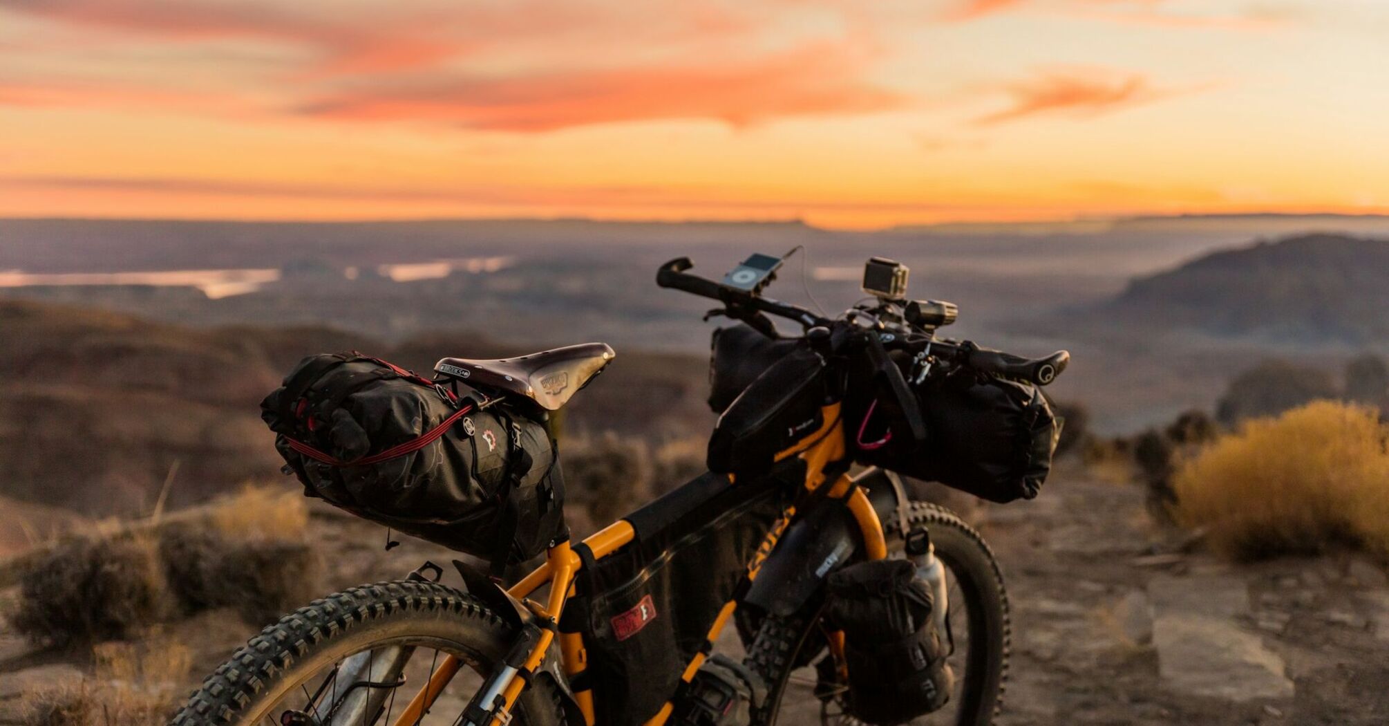 Loaded bicycle with gear at sunset overlooking a scenic landscape