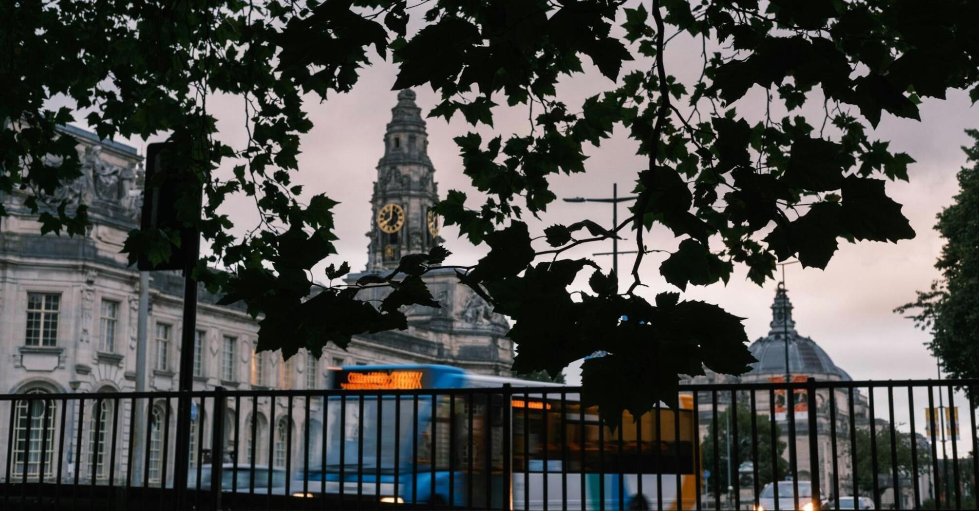 View of Cardiff's historic buildings through the leaves with a bus passing by