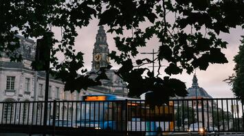 View of Cardiff's historic buildings through the leaves with a bus passing by