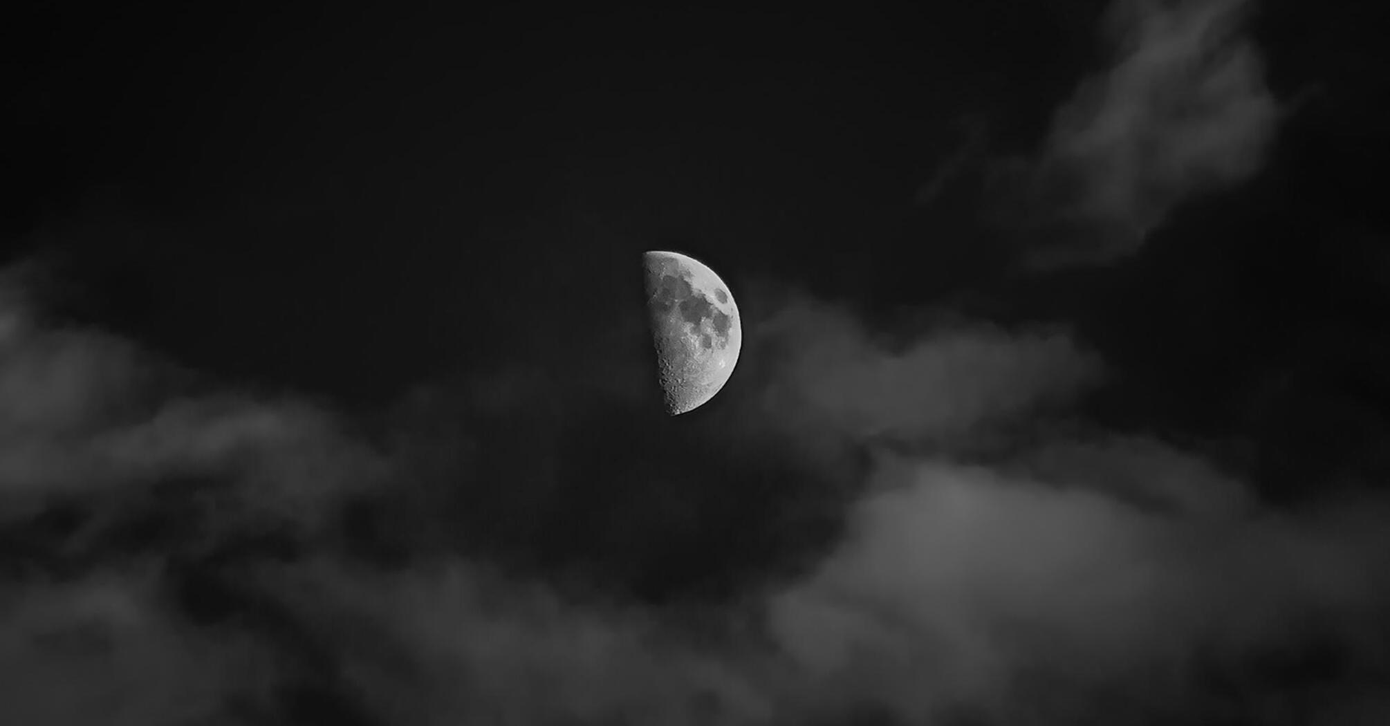 Half moon through clouds in the night sky