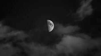 Half moon through clouds in the night sky