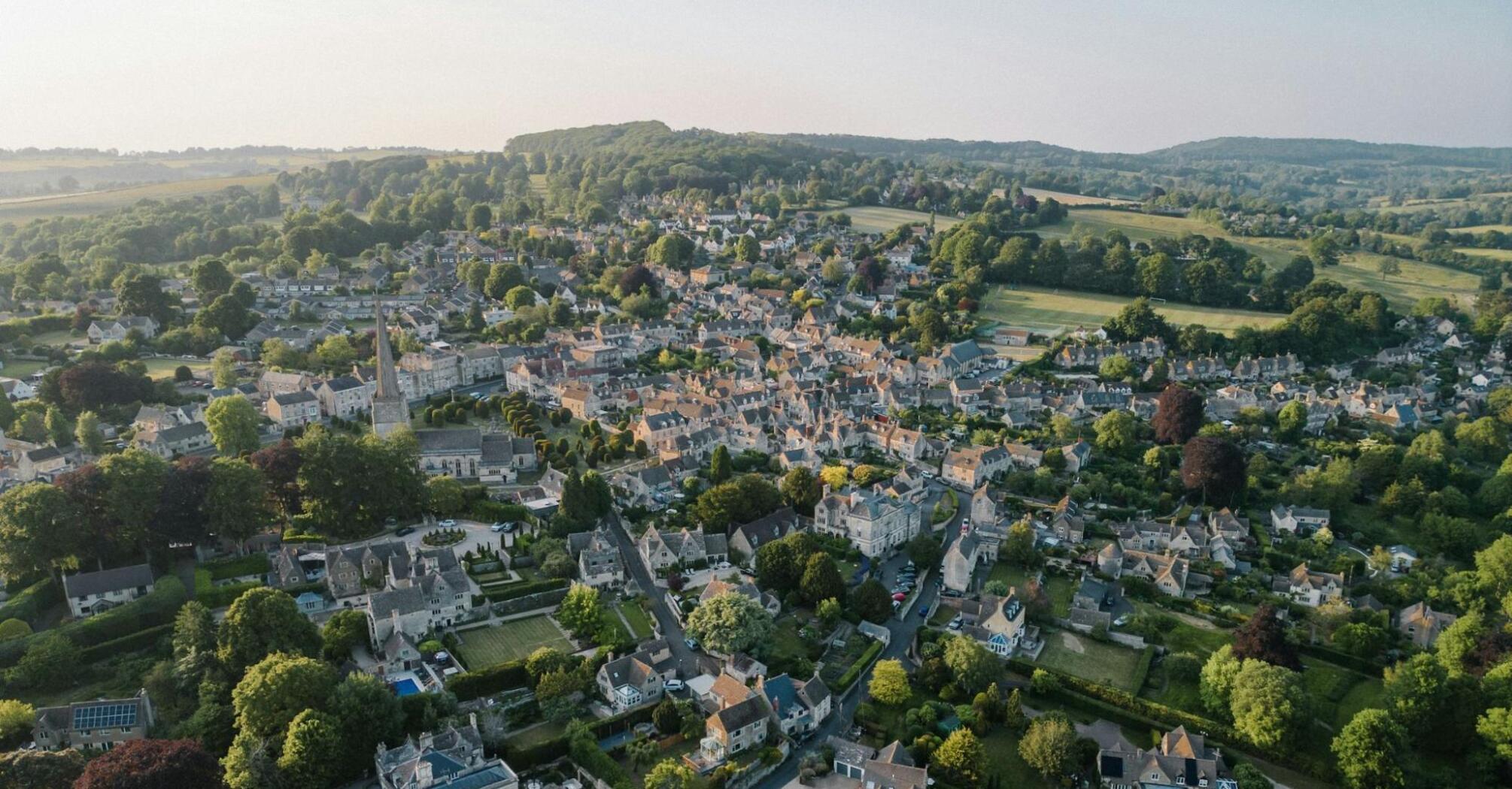 Aerial view of a charming village in the South Cotswolds, featuring historic buildings and lush greenery