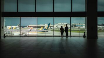 Two people looking at planes at an airport
