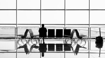 A lone traveler waits at an airport gate