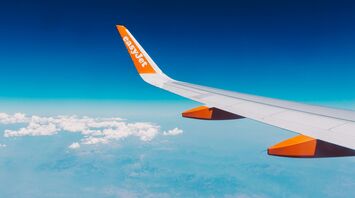 easyJet airplane wing flying above clouds and coastline