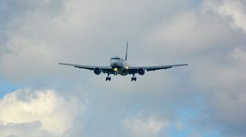 Airplane approaching for landing against cloudy sky
