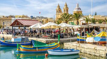 Vibrant waterfront scene in Malta with colorful boats and outdoor cafes