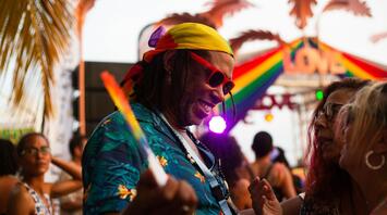 People dancing at a vibrant LGBTQ+ celebration with rainbow flags