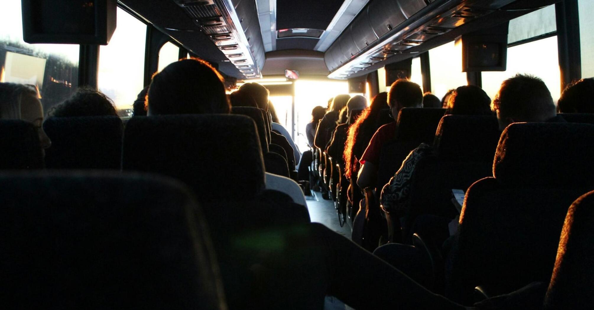 Passengers seated inside a bus during sunset