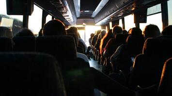 Passengers seated inside a bus during sunset