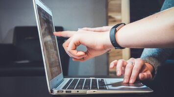 Two people pointing at a laptop screen