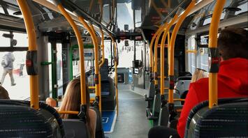 Passengers inside a modern bus with yellow handrails