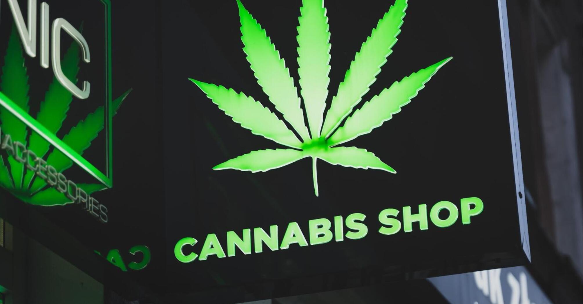 Illuminated "CANNABIS SHOP" sign with a cannabis leaf image