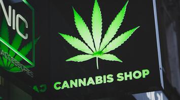Illuminated "CANNABIS SHOP" sign with a cannabis leaf image