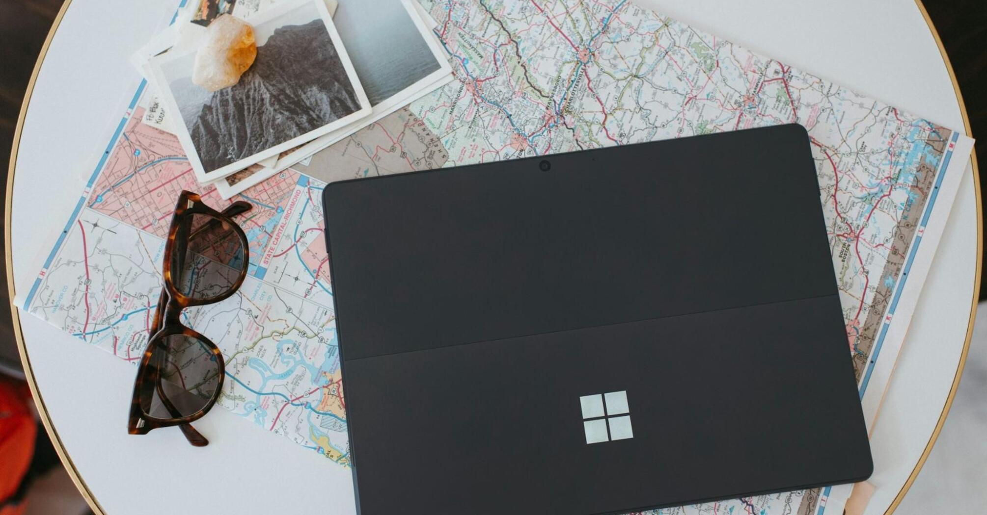 Laptop, sunglasses, and travel maps on a table