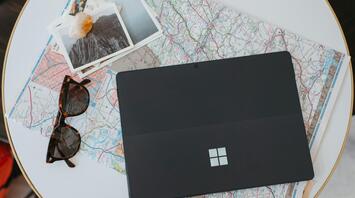 Laptop, sunglasses, and travel maps on a table