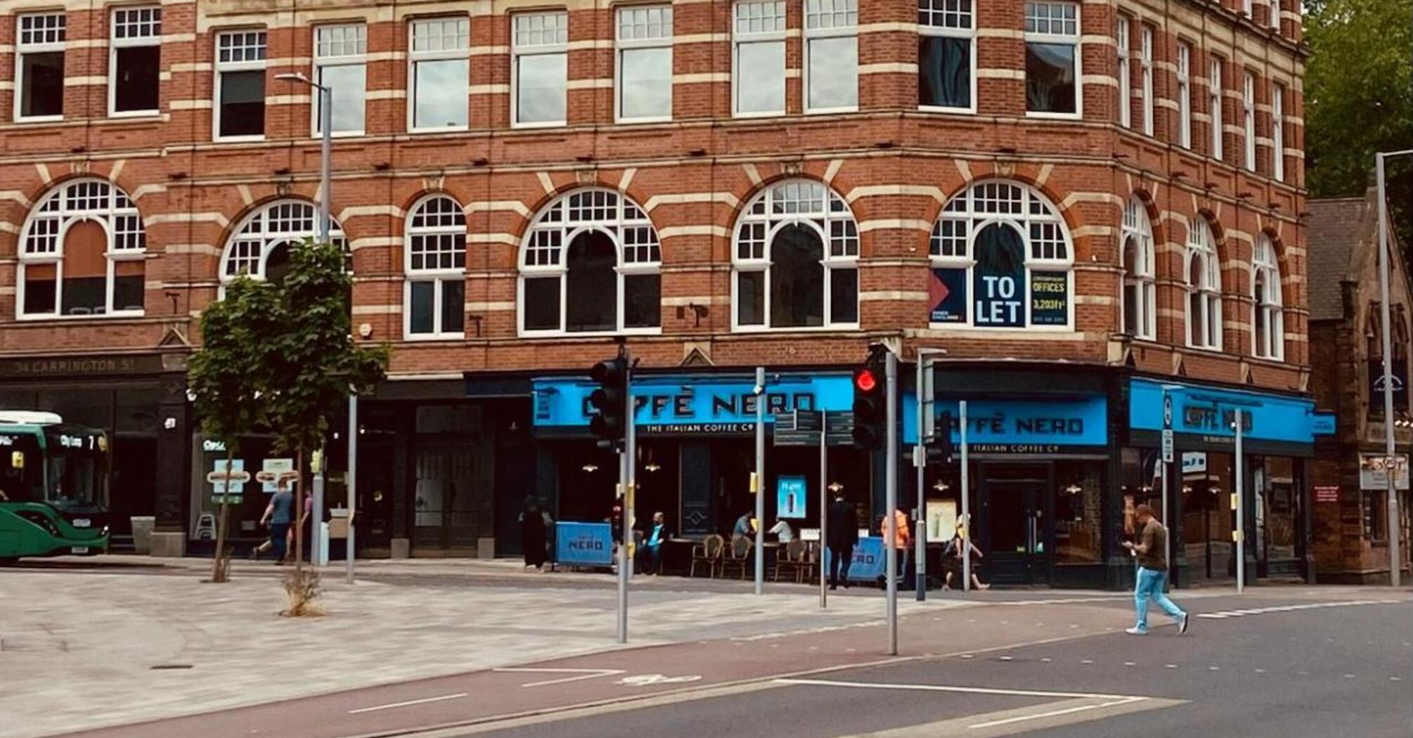 Historic brick building with a clock tower and a bus on the left, located in Nottingham