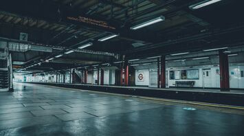 A deserted platform at London Liverpool Street station with overhead signs and empty benches