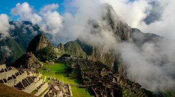 Aerial view of Machu Picchu with surrounding mountains and clouds