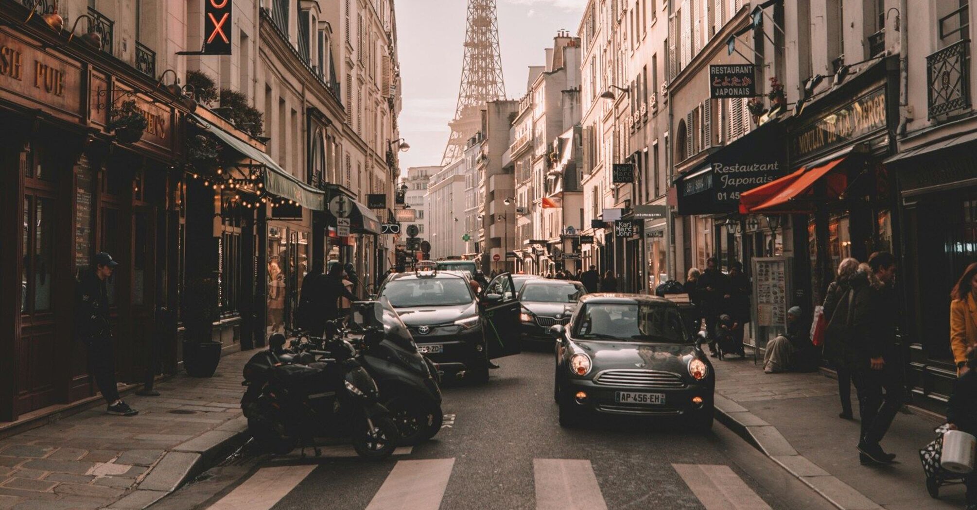 Street view of Paris with the Eiffel Tower in the background and various restaurants and shops