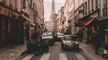 Street view of Paris with the Eiffel Tower in the background and various restaurants and shops