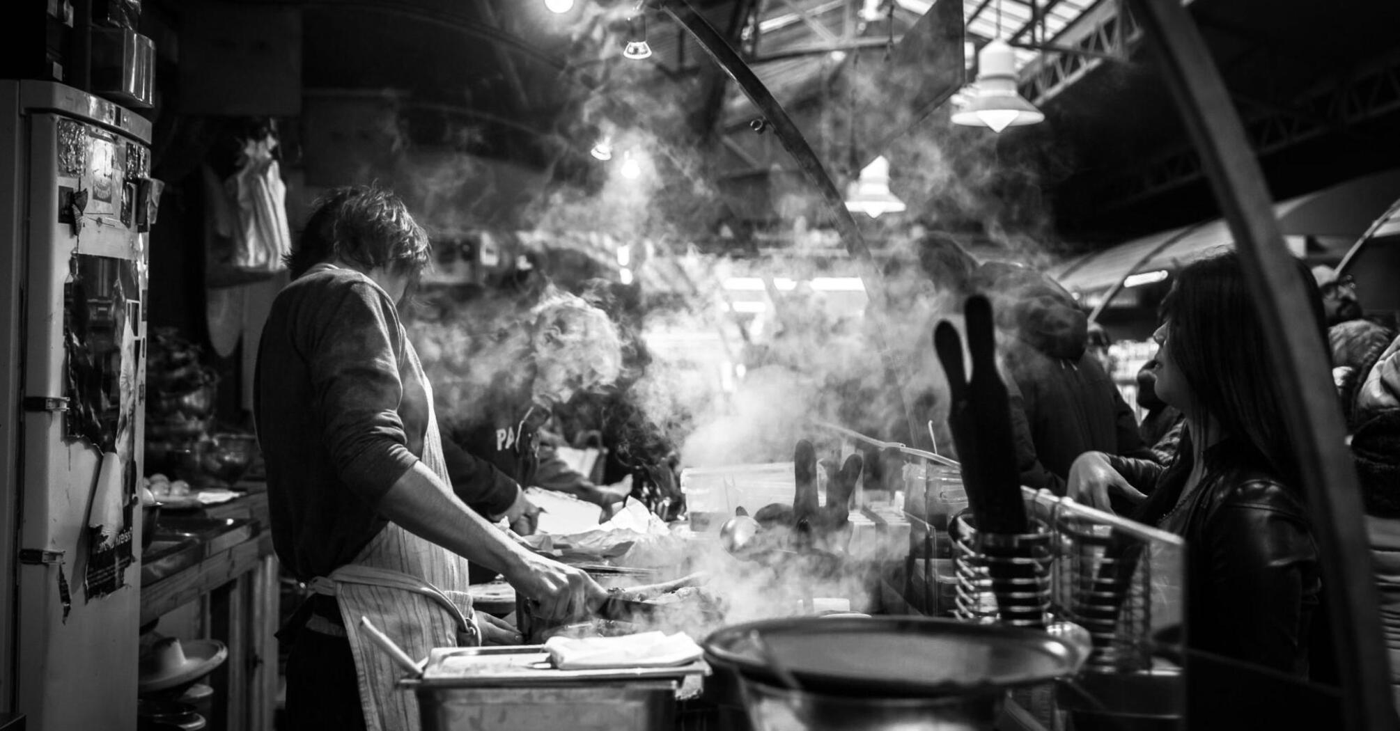 Man preparing food in a crowded street kitchen