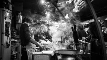 Man preparing food in a crowded street kitchen