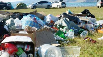 Garbage and plastic bottles are scattered on the shore of the lake
