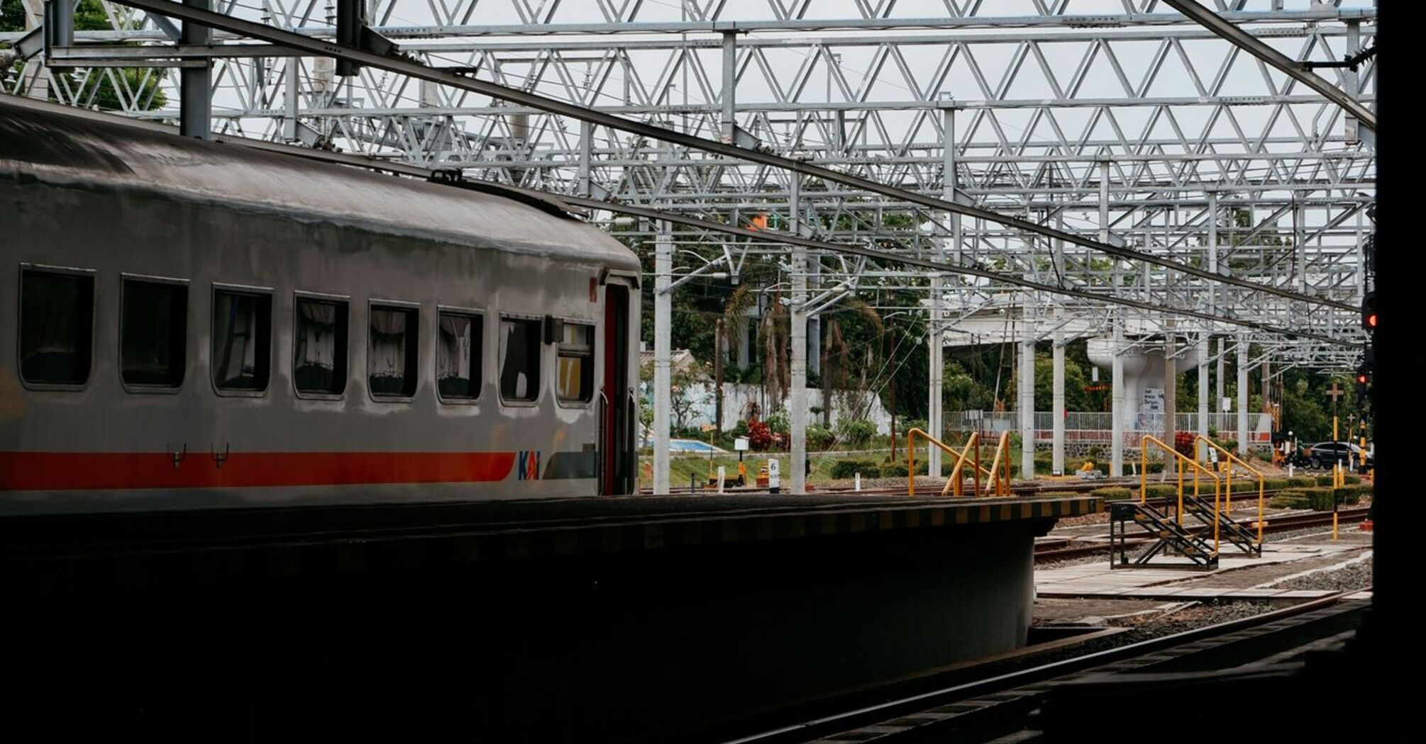 A train at a station platform with railway tracks and overhead structures