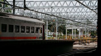 A train at a station platform with railway tracks and overhead structures