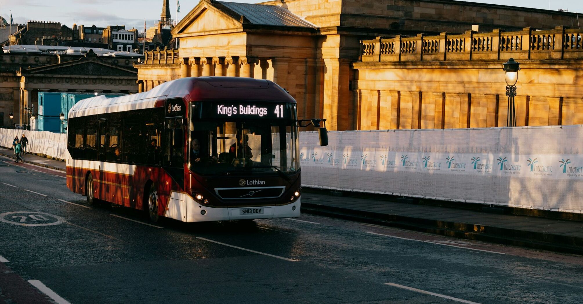 A Lothian Buses bus on route 41 passing by historical buildings in Edinburgh during early morning light