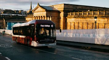 A Lothian Buses bus on route 41 passing by historical buildings in Edinburgh during early morning light