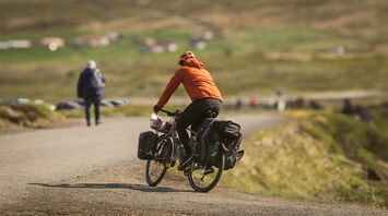 Person cycling on a rural path with scenic background