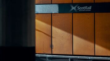 A ScotRail station platform with orange walls and the ScotRail logo